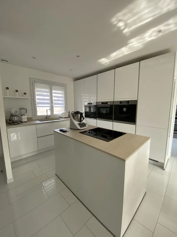 Cuisine blanche brillante avec îlot central au design épuré, réalisée par Cuisines ELITE Osny, vue 1 sur 2