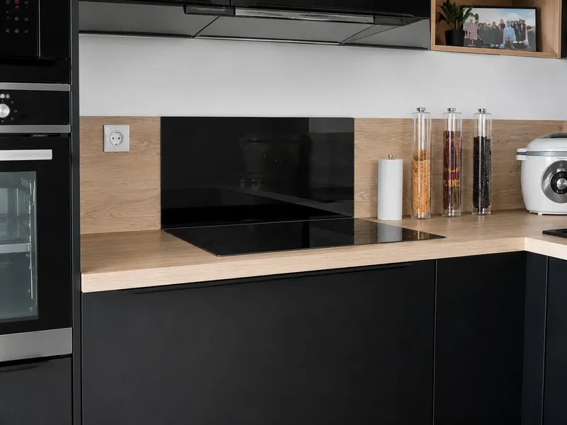 Cuisine noire mate avec îlot central et plan de travail effet bois au style…, réalisée par Cuisines ELITE Osny, vue 1 sur 4